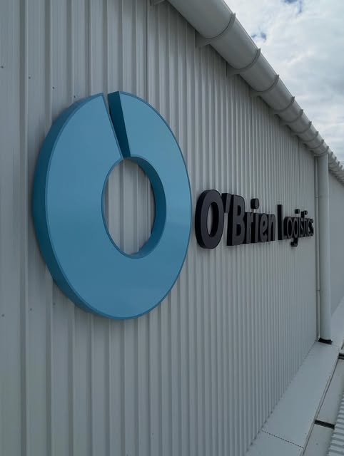 Large fabricated 3D logo disc mounted to an industrial wall
